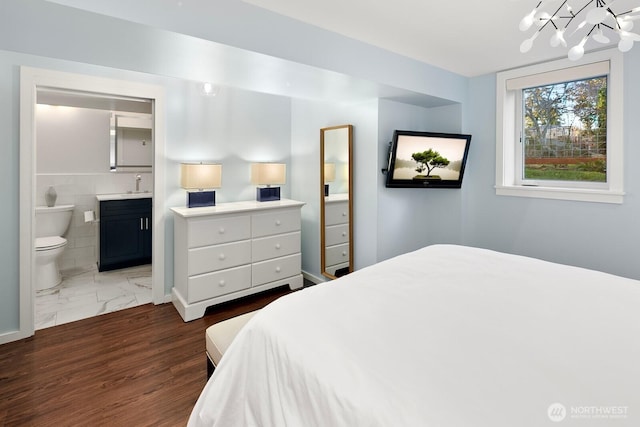 bedroom featuring ensuite bathroom, marble finish floor, a sink, and a notable chandelier