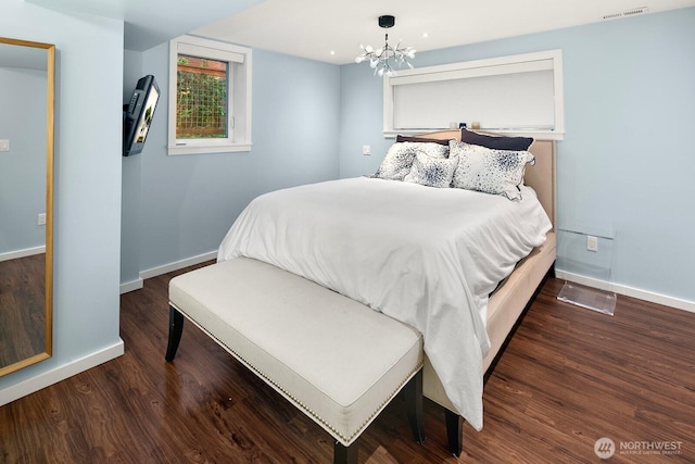 bedroom featuring a chandelier, visible vents, baseboards, and wood finished floors