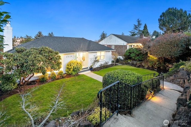 view of front of home with a shingled roof and a front yard