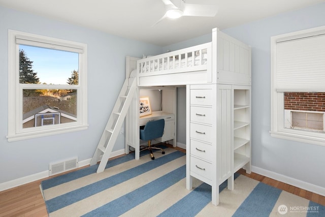 bedroom with a ceiling fan, baseboards, visible vents, and wood finished floors