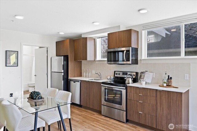 kitchen featuring a sink, light countertops, light wood-type flooring, and stainless steel appliances