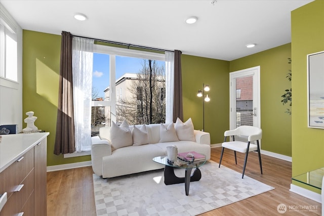 living area with a wealth of natural light, baseboards, and light wood-style floors