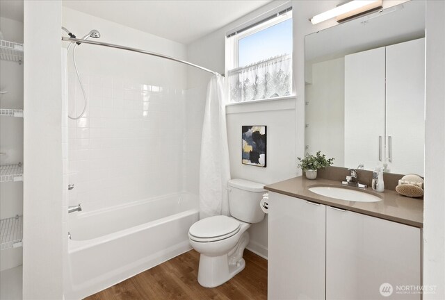 bathroom with vanity, toilet, wood finished floors, and shower / tub combo with curtain