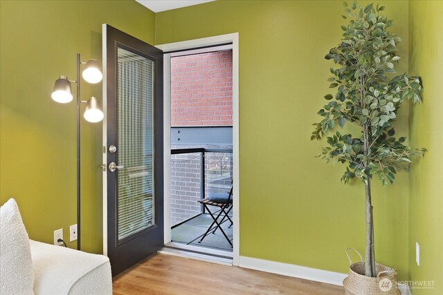 doorway featuring baseboards and wood finished floors