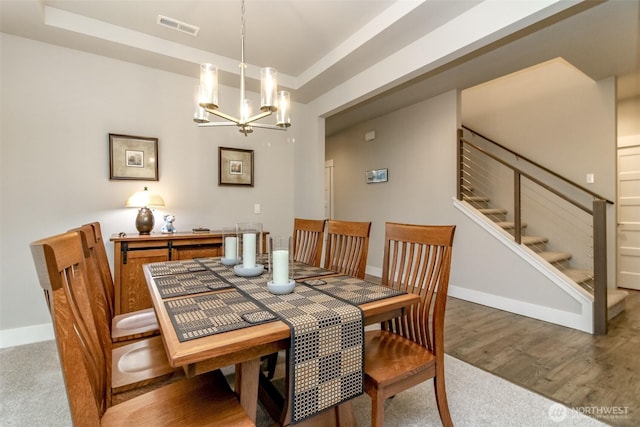 dining space with stairway, wood finished floors, baseboards, visible vents, and a chandelier