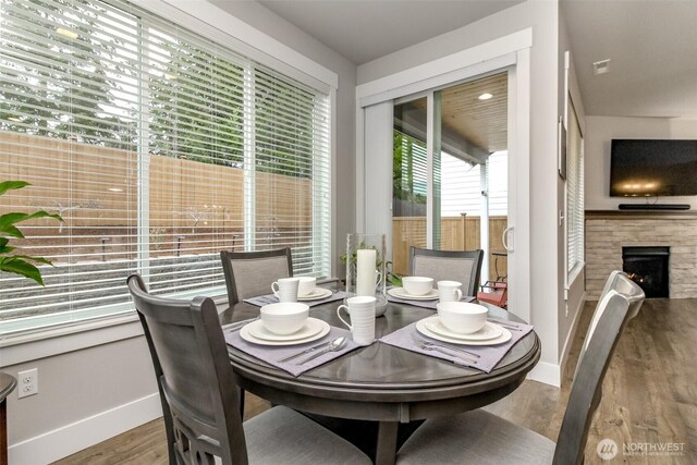 dining area featuring a fireplace, baseboards, and wood finished floors