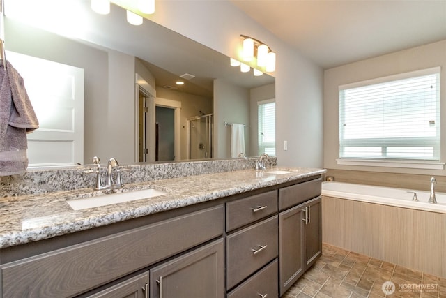 bathroom featuring double vanity, a stall shower, and a sink