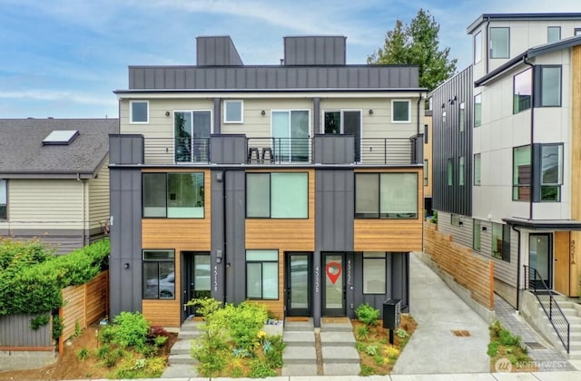 exterior space with metal roof, a balcony, fence, board and batten siding, and a standing seam roof