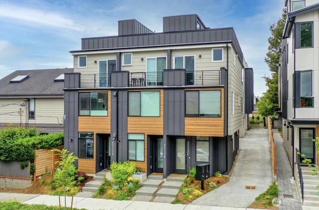 view of front of property featuring a balcony, metal roof, a standing seam roof, fence, and board and batten siding