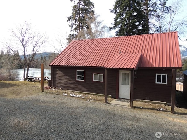 view of side of home with a mountain view, metal roof, and an outdoor structure