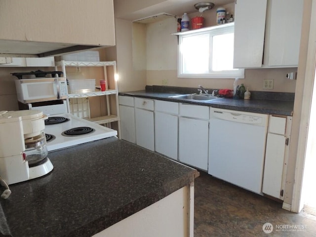 kitchen with dark countertops, white cabinets, white appliances, and a sink