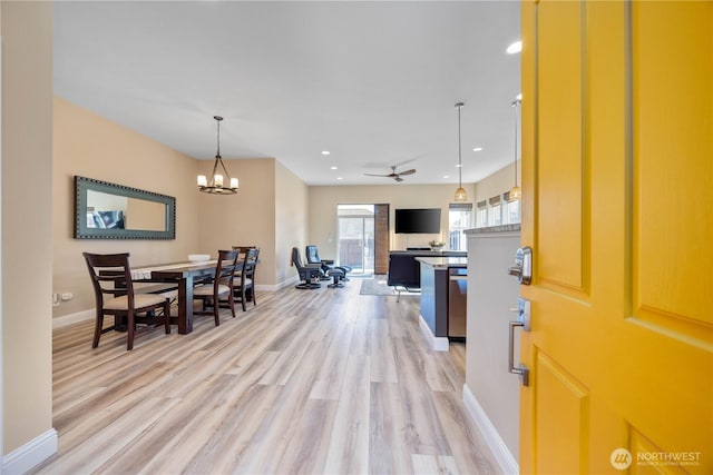 interior space featuring light wood-style flooring, ceiling fan with notable chandelier, baseboards, and recessed lighting