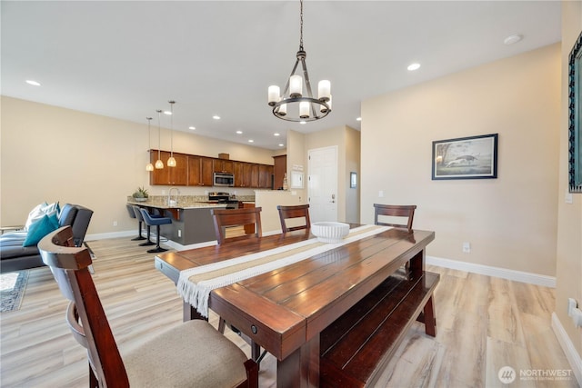 dining space with light wood finished floors, recessed lighting, an inviting chandelier, and baseboards