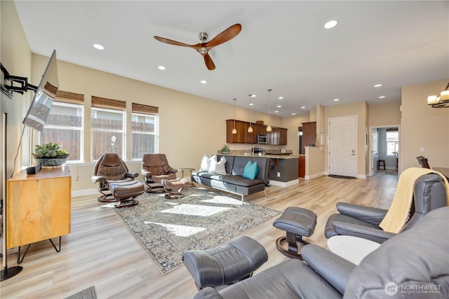 living area with baseboards, ceiling fan with notable chandelier, light wood-type flooring, and recessed lighting