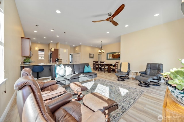 living room with light wood-style flooring, ceiling fan with notable chandelier, baseboards, and recessed lighting