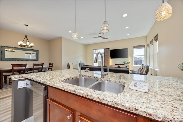 kitchen featuring light stone counters, recessed lighting, a sink, stainless steel dishwasher, and pendant lighting