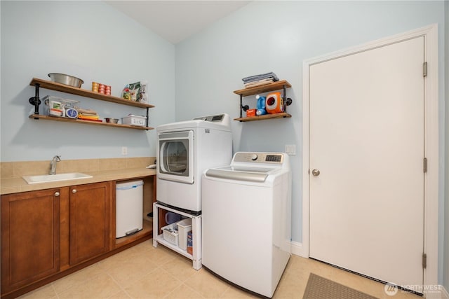 clothes washing area with separate washer and dryer, a sink, and cabinet space