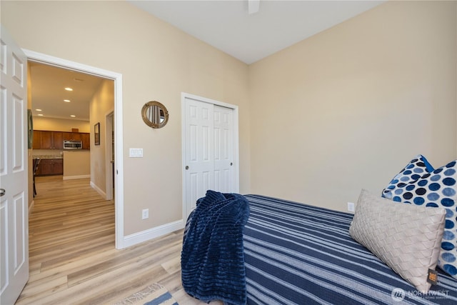 bedroom featuring recessed lighting, a closet, light wood-style flooring, and baseboards