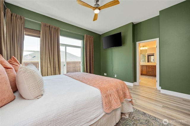 bedroom with light wood finished floors, ensuite bath, a ceiling fan, and baseboards