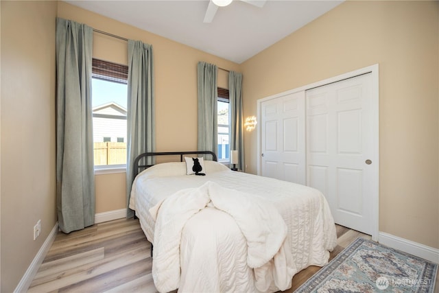 bedroom featuring light wood finished floors, a ceiling fan, baseboards, and a closet