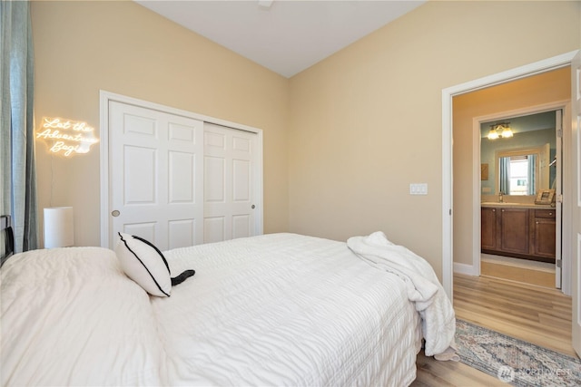 bedroom with baseboards, a closet, a sink, and light wood-style floors