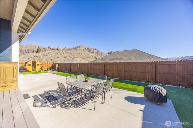 view of patio / terrace with outdoor dining area, a fenced backyard, and a mountain view