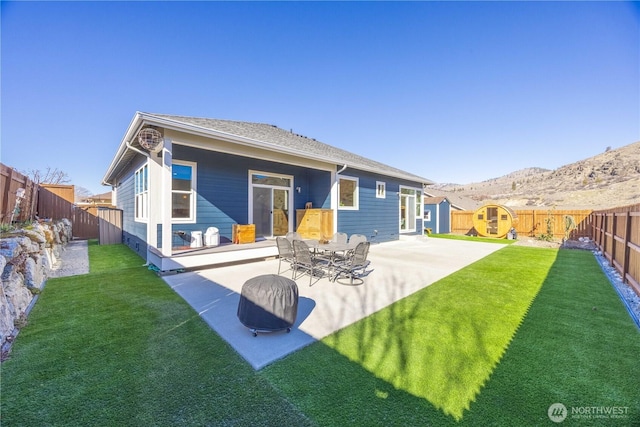 rear view of house with a lawn, a patio area, a fenced backyard, and a mountain view