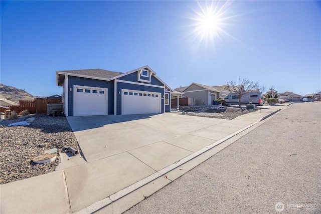 ranch-style house featuring a garage, concrete driveway, fence, and a residential view