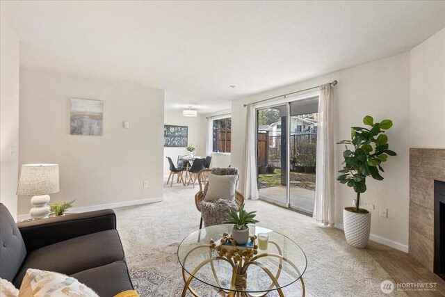 living room with light carpet, baseboards, and a tiled fireplace