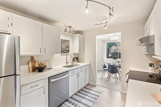 kitchen with under cabinet range hood, stainless steel appliances, a sink, white cabinets, and light countertops