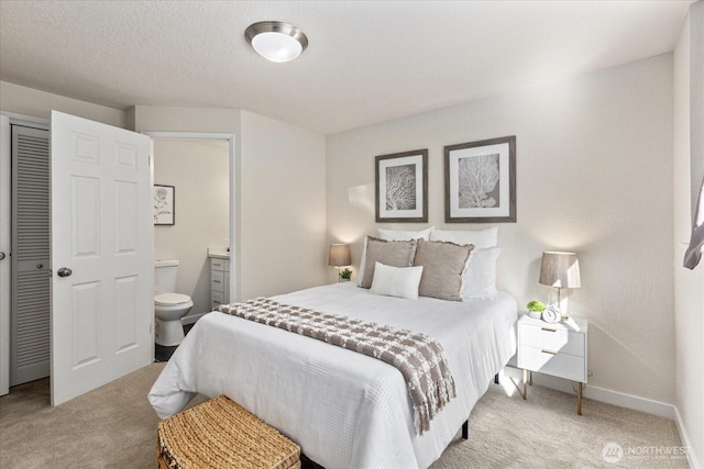 bedroom with baseboards, ensuite bathroom, carpet, a textured ceiling, and a closet