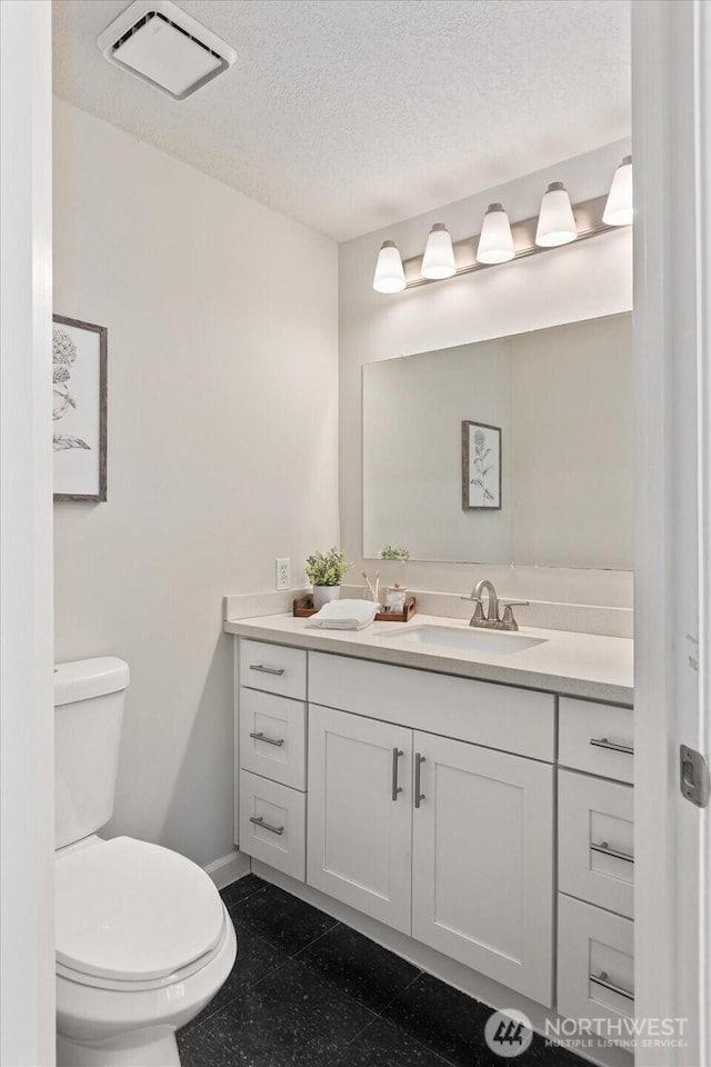 bathroom with visible vents, toilet, vanity, a textured ceiling, and baseboards