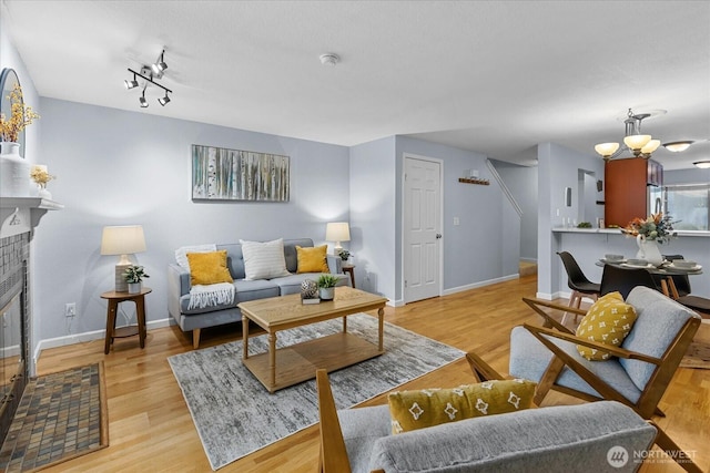 living room featuring a fireplace, light wood-style flooring, and baseboards