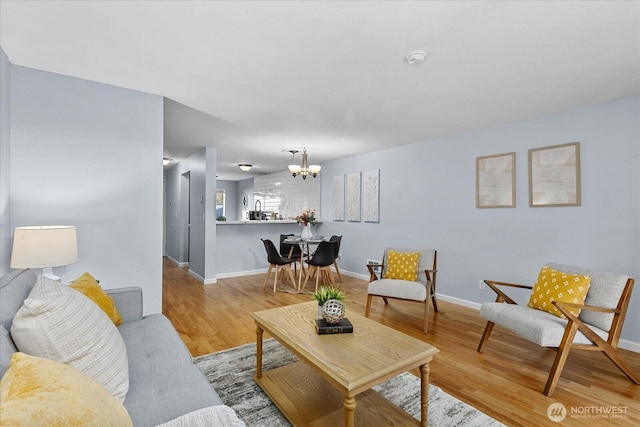 living room with a chandelier, wood finished floors, and baseboards