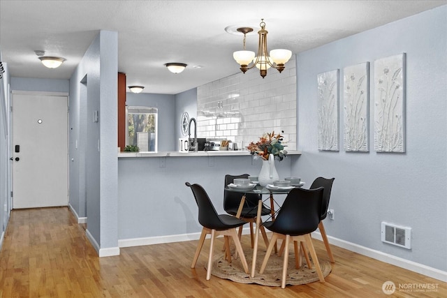 dining space featuring baseboards, visible vents, an inviting chandelier, and wood finished floors