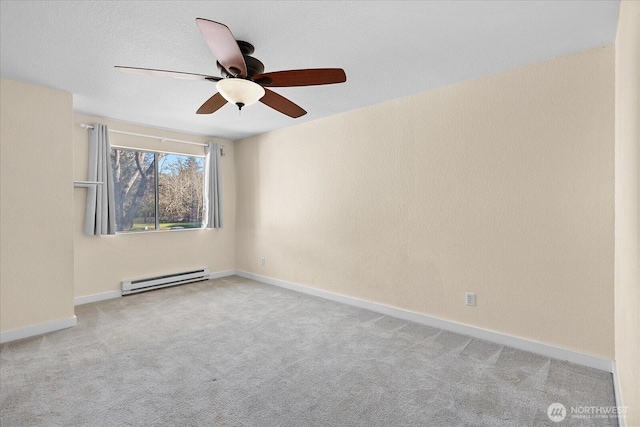 carpeted spare room with a baseboard heating unit, a ceiling fan, and baseboards