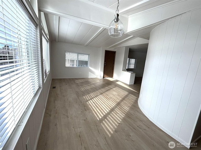 interior space with lofted ceiling with beams, wood finished floors, and visible vents