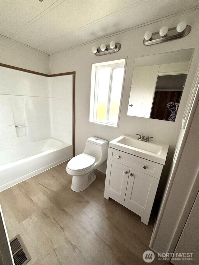 bathroom featuring vanity, wood finished floors, visible vents, tub / shower combination, and toilet