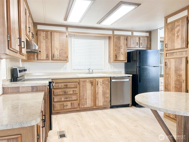 11436 SE 208th St Unit 106, Kent, WA 98031 - kitchen featuring light wood finished floors, under cabinet range hood, light countertops, a sink, and appliances with stainless steel finishes