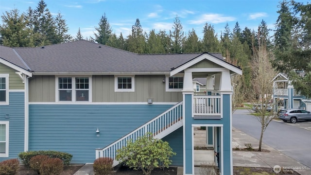 exterior space featuring a shingled roof, stairs, and board and batten siding