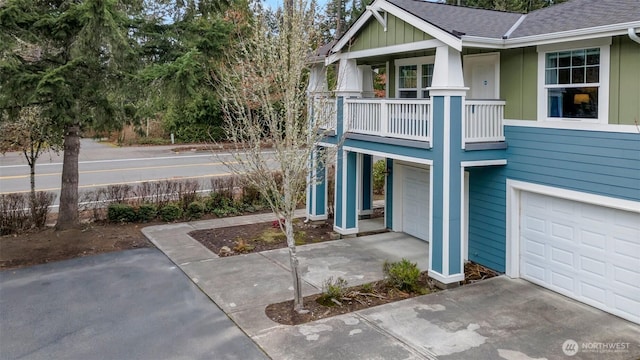 view of front of house featuring board and batten siding, an attached garage, concrete driveway, and roof with shingles