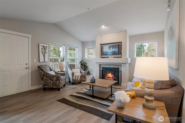 interior space with lofted ceiling, a tile fireplace, wood finished floors, and baseboards