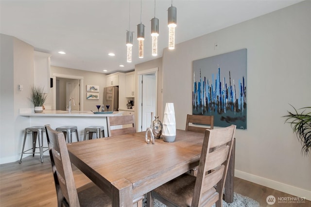 dining room with light wood-type flooring, baseboards, and recessed lighting