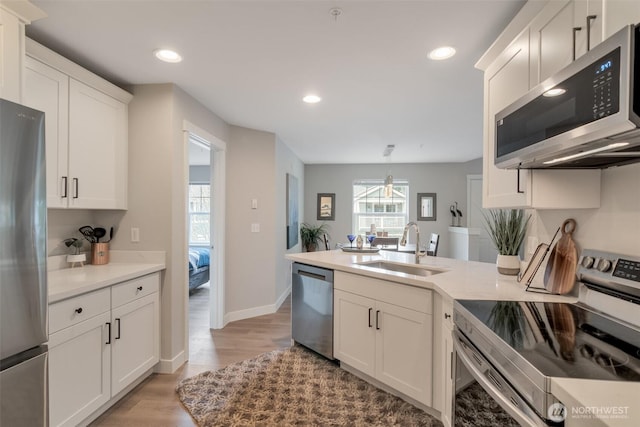 kitchen with a peninsula, plenty of natural light, appliances with stainless steel finishes, and a sink