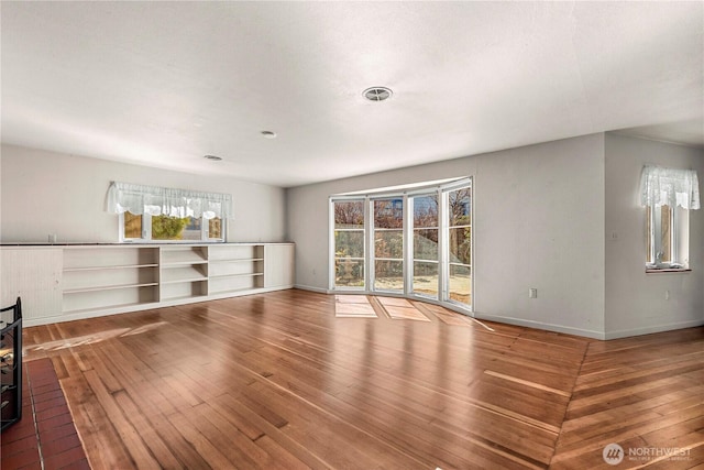 unfurnished room with hardwood / wood-style flooring, visible vents, and baseboards