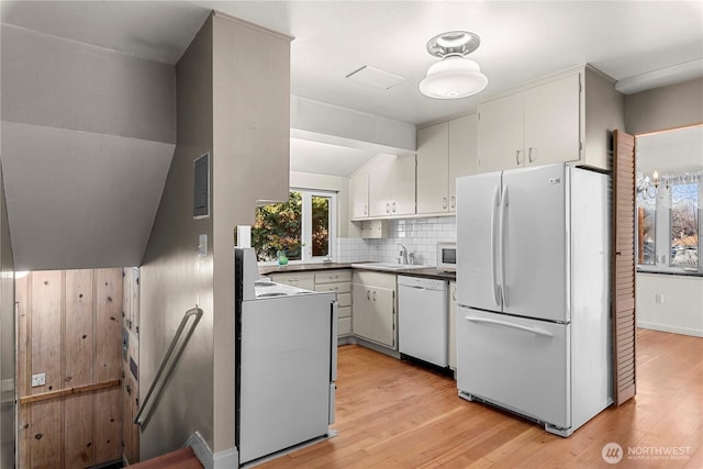 kitchen with white appliances, a sink, white cabinets, backsplash, and light wood finished floors