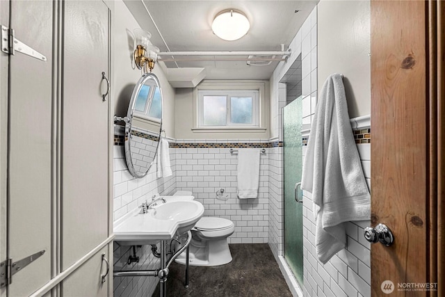 full bathroom featuring toilet, a wainscoted wall, a shower stall, and tile walls