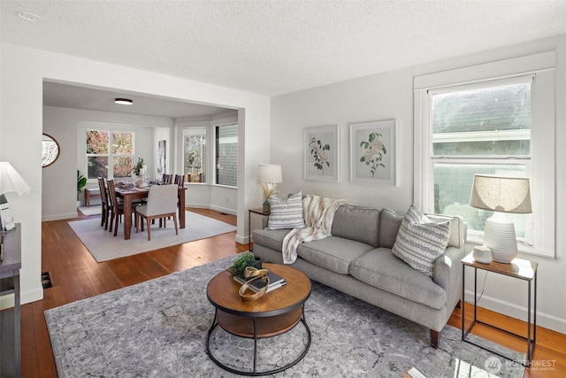 living area featuring wood-type flooring, a textured ceiling, and baseboards