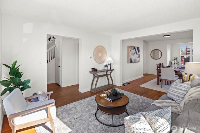 living area with a textured ceiling, baseboards, and wood finished floors