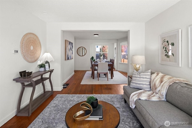 living room with wood finished floors, visible vents, and baseboards